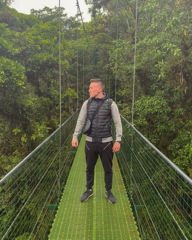 Arthur standing on a jungle suspension bridge