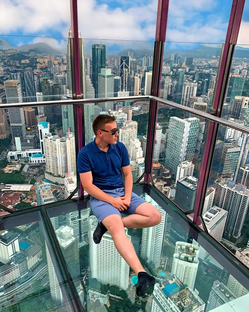 Arthur sitting in a glass sky box high above Kuala Lumpur
